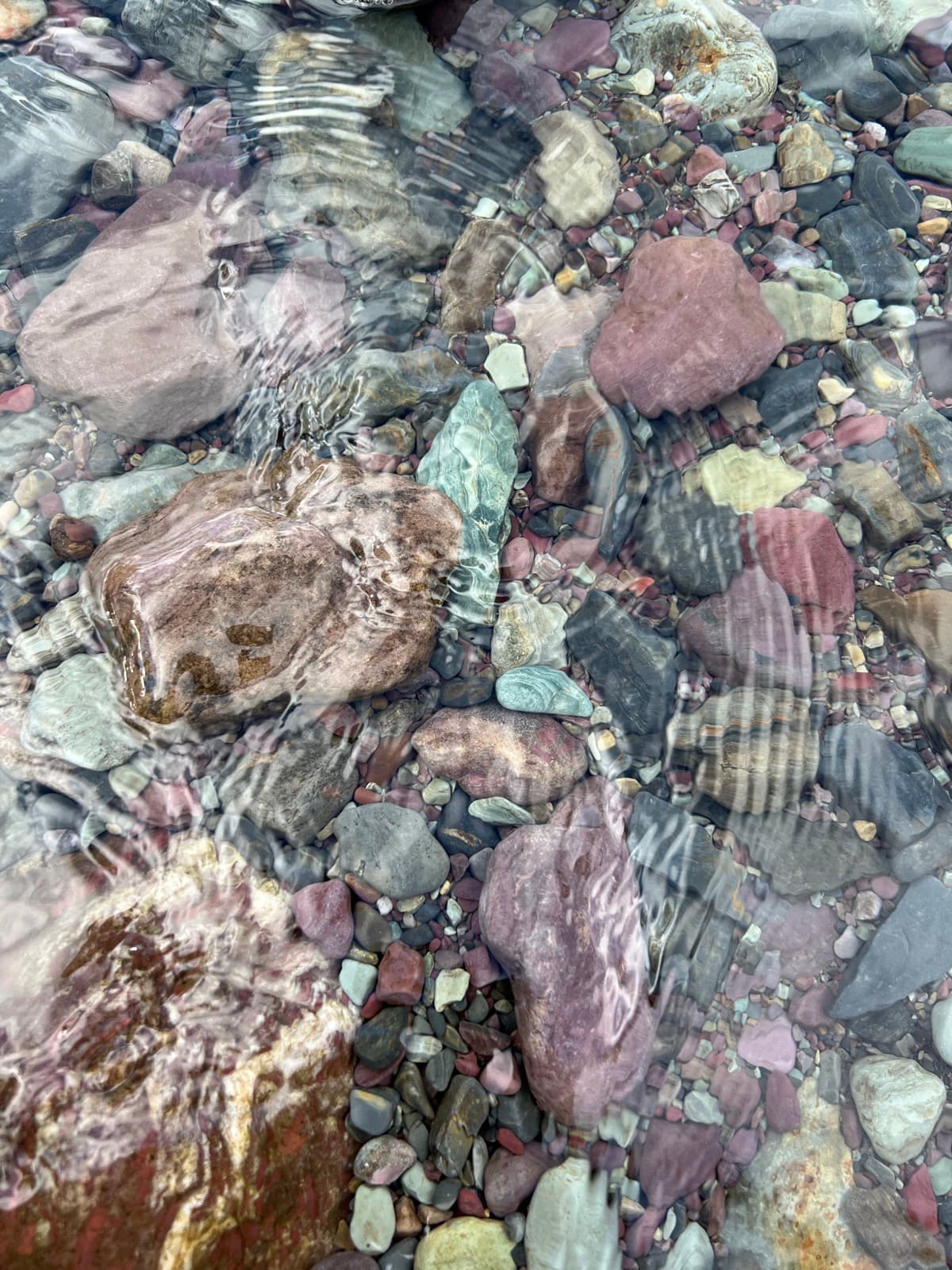 Coloured river stones beneath clear moving water